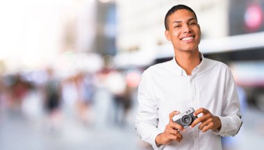 Beyaz gömlek şehrin ortasında bir kamera tutan genç Afro-Amerikan adamla
