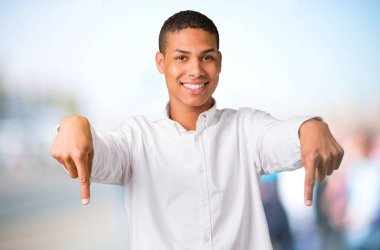 Parmakları odaklanmamış açık arka plan üzerinde beyaz gömlek aşağıyı ile genç Afro-Amerikan adam