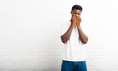 Koyu tenli adam biraz gergin ve korkmuş ellerini ağzına koyarak