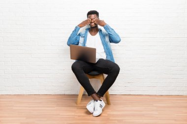 Afro Amerikalı adam gözleri eller tarafından kapsayan onun laptop ile çalışma