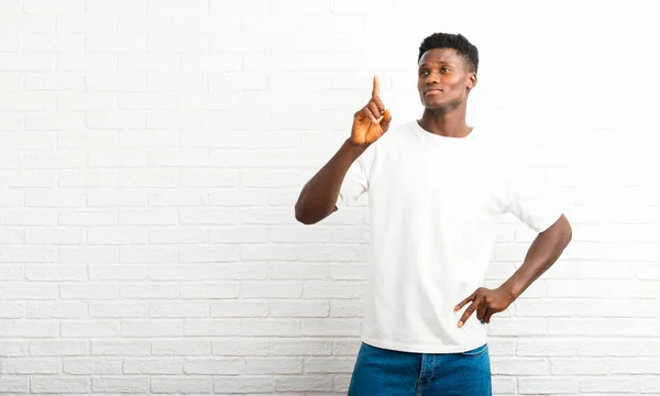Dark skinned man showing and lifting a finger in sign of the best