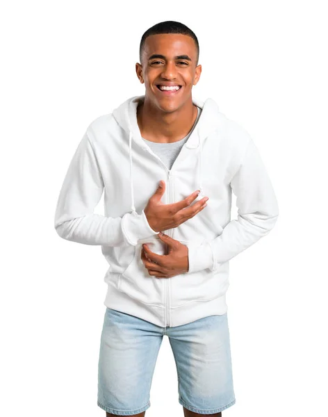 深色皮肤的年轻人与白色运动衫微笑很多 而把手放在查出的白色背景的胸部 — 图库照片