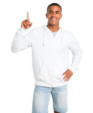 Esmer genç adam ile gösterilen ve işareti en iyi izole beyaz zemin üzerinde bir parmak kaldırma beyaz sweatshirt