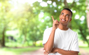 İşaret parmağı ile harika bir fikir ve bir parkta ararken genç Afro-Amerikan adam