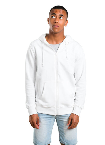 Dark-skinned young man with white sweatshirt stand and looking up with serious face on isolated white background