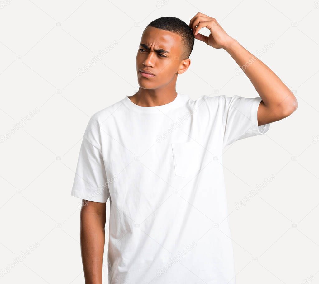 Young african american man having doubts and with confuse face expression while scratching head on isolated background