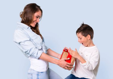 Anne ve kızı bir hediye mavi arka plan üzerinde tutan