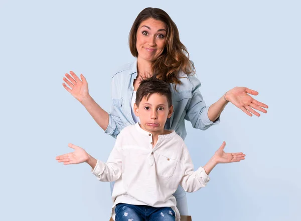 Mother and daughter having doubts and with confuse face expression on blue background