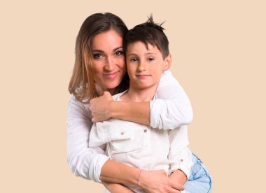 Anne ve oğlu koyu sarı arka plan üzerinde gülüyor