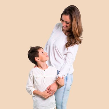 Anne ve oğlu koyu sarı arka plan üzerinde gülüyor