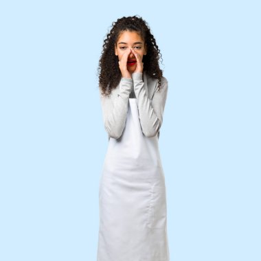 İzole mavi arka plan üzerine açık ağızlı bağırmayı önlük ile genç kız