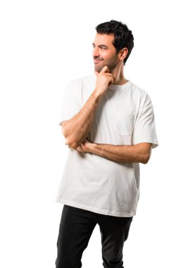 Genç adamla ayakta ve çene izole beyaz arka planda üzerinde el ile tarafına bakarak beyaz gömlek