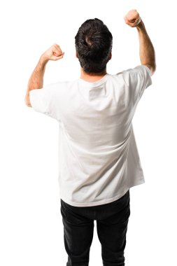 Genç adam ile beyaz gömlek bir zaferini kutluyor ve izole beyaz arka plan üzerinde başarılı olmak için sürpriz