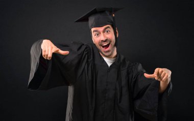 Adam birine parmak ile işaret ve siyah arka plan üzerine çok gülerek onun mezuniyet günü Üniversitesi Tarih