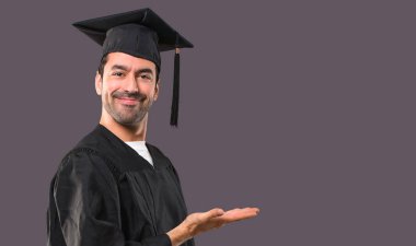 Adam bir ürün ya da bir fikir görünümlü doğru menekşe arka plan üzerinde gülümseyen süre sunulması onun mezuniyet günü Üniversitesi Tarih