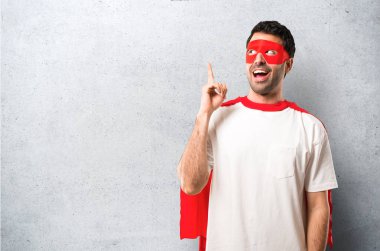 Süper kahraman maske ve kırmızı pelerin anlar çözüm dokulu gri arka plan üzerinde parmak kaldırma süre isteyen adamla