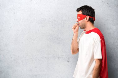 Süper kahraman adam maskesi ve kırmızı pelerin ile öksürük acı ve dokulu gri arka plan üzerinde kötü hissediyor