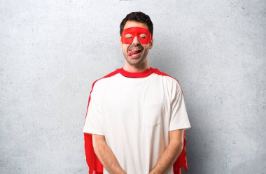 Süper kahraman maske ve kırmızı pelerin adamla komik ve çılgın yüz duygu dokulu gri arka plan üzerinde yapar.