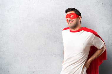 Süper kahraman maske ve kırmızı pelerin mutsuz ve bir çaba dokulu gri arka plan üzerinde yapılmış olan sırt ağrısı acı adamla