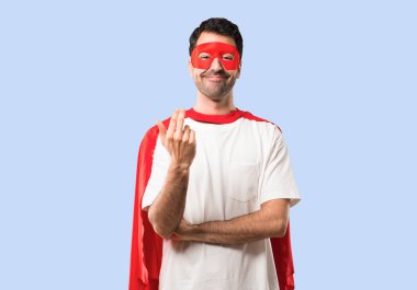 Süper kahraman adam sunulması ve el ile gelmek davet maskesi ve kırmızı pelerin. Mutlu izole mavi arka plan üzerinde geldi