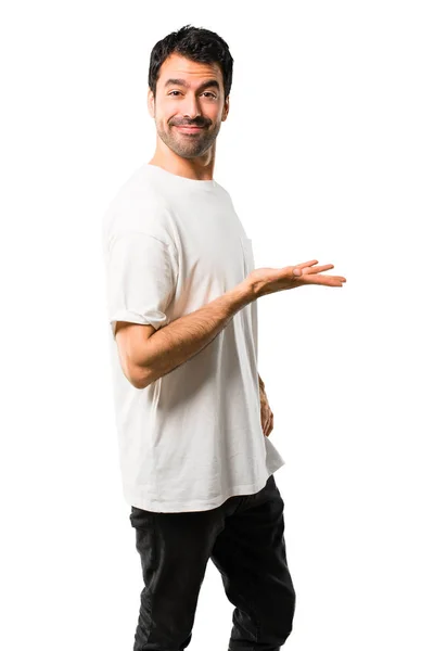 穿着白衬衫的年轻人一边展示一个产品或一个想法 一边在孤立的白色背景上面带微笑 — 图库照片