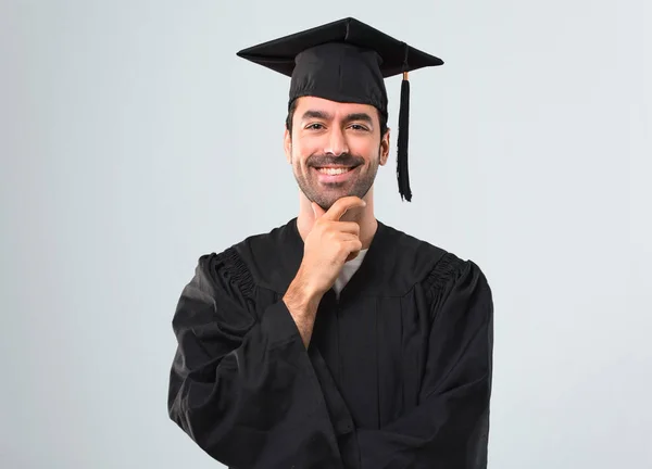 笑顔と灰色の背景に自信を持って顔を正面に見て彼の卒業日大学の男 — ストック写真