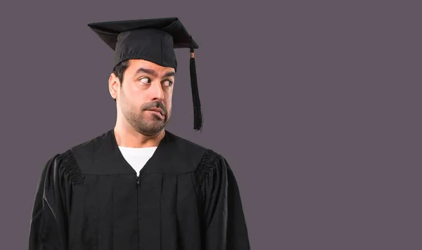 彼の卒業の日の大学の男はもう少し緊張感と恐怖を押して歯紫色の背景に — ストック写真