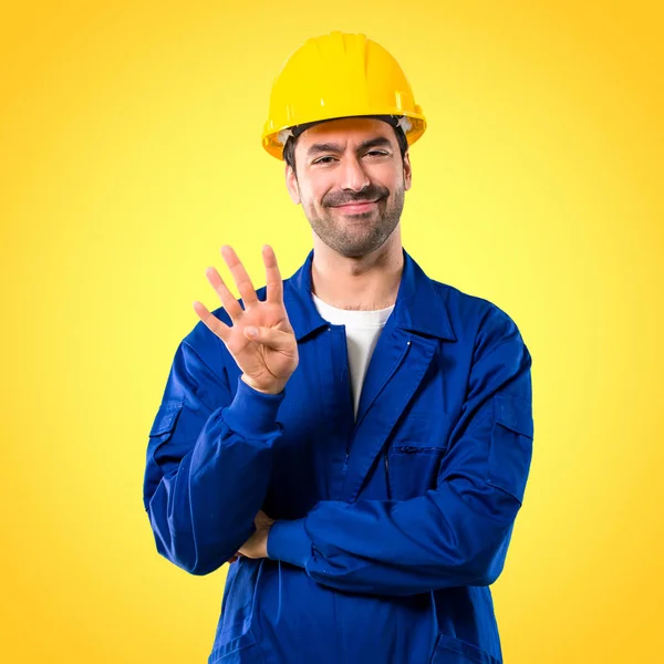黄色の背景に指でヘルメット幸せと数える 若い職人 — ストック写真