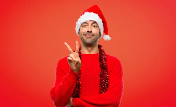 幸せなクリスマスを祝うと赤い背景の上の指を持つ つを数える赤い服の男 — ストック写真