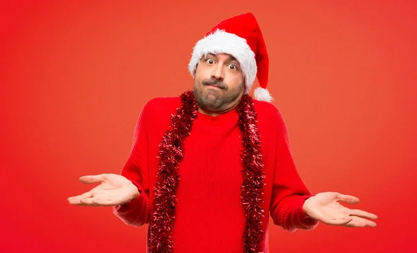 赤い服を着て赤い背景に肩を持ち上げながら重要でないジェスチャーを作るクリスマス休暇を祝う男 — ストック写真