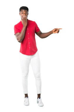 Parmak tarafına işaret ve ağız beyaz arka plan üzerinde kapsayan süre sürpriz bir yüzle bir ürün sunma Afrikalı-Amerikalı gencin tam vücut
