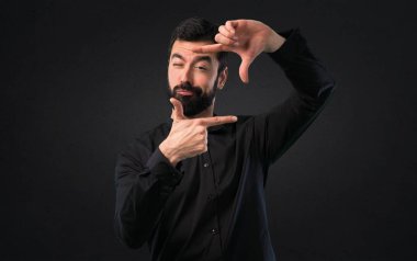 Sakal parmaklarıyla siyah arka plan üzerine odaklanan yakışıklı adam
