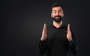 Bir şey siyah arka planda tutan sakallı yakışıklı adam