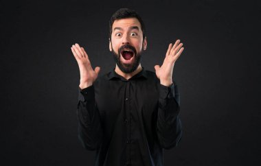 Siyah arka plan üzerine sakal yapma sürpriz hareketi ile yakışıklı adam