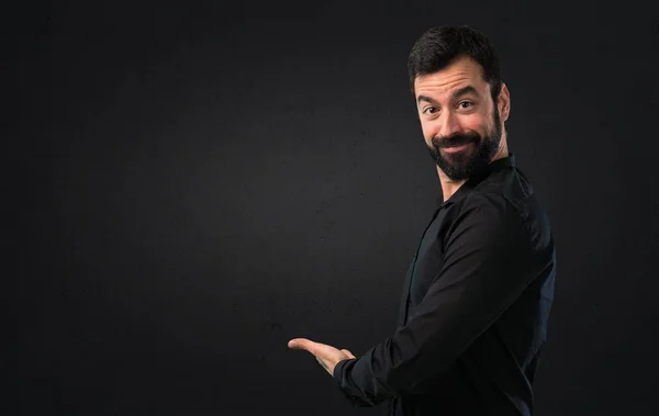 Hombre Guapo Con Barba Presentando Algo Sobre Fondo Negro — Foto de Stock