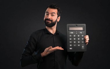Bir hesap makinesi siyah arka plan üzerine tutarak sakallı yakışıklı adam