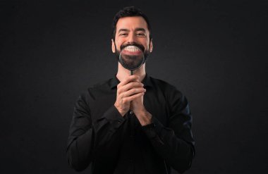 Siyah arka plan üzerine büyüteç ile sakallı yakışıklı adam