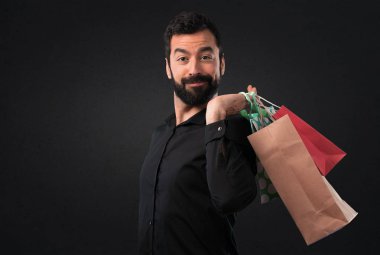 Siyah arka plan üzerine alışveriş çantası ile sakallı yakışıklı adam