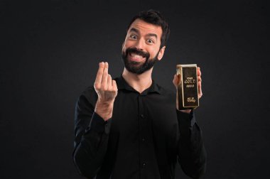 Siyah zemin üzerine altın külçe ile sakallı yakışıklı adam