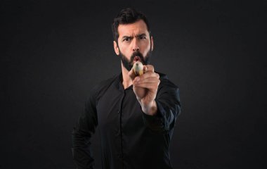 Siyah arka plan üzerine büyük bir kalem tutan sakallı yakışıklı adam