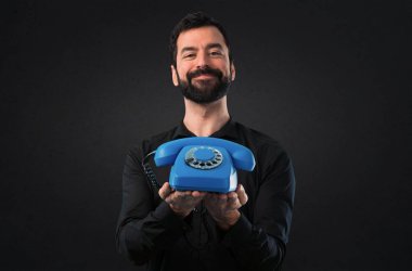 Siyah arka plan üzerine konuşmak için vintage telefon sakallı yakışıklı adam