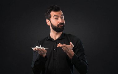 Siyah arka plan üzerine bir oyuncak uçak holding sakallı yakışıklı adam