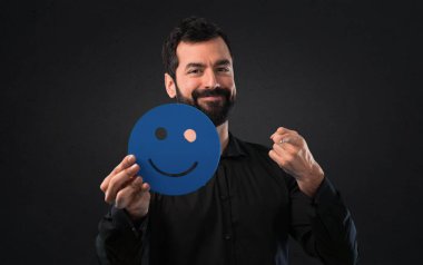 Mutlu yüz simgesi siyah arka plan üzerine tutarak sakallı yakışıklı adam