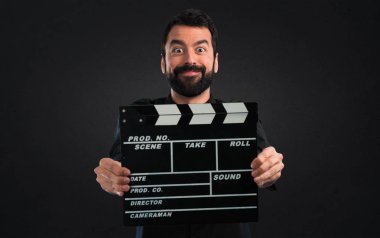 Siyah arka plan üzerine bir Klaket tutan sakallı yakışıklı adam