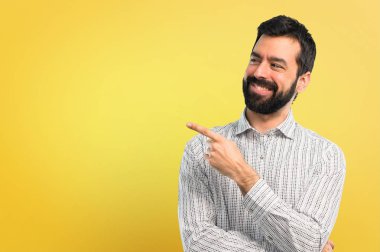 Parmak tarafına işaret ve bir ürün sunma sakallı yakışıklı adam