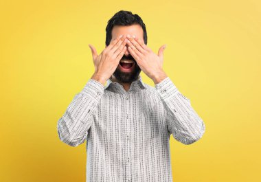 Gözleri eller tarafından kapsayan sakallı yakışıklı adam