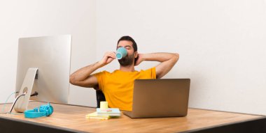 Laptot kahve tutan bir ofiste çalışan adam