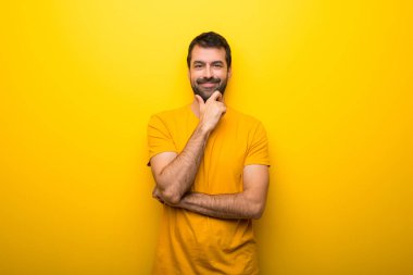 Adam gülümseyerek ve öne doğru emin yüz ile seyir izole canlı sarı renk