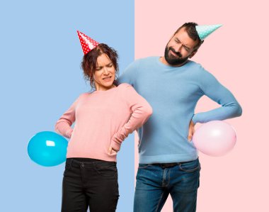 Balonlar ve bir çaba pembe ve mavi arka plan üzerinde yapılmış olan sırt ağrısı muzdarip Doğum günü şapka ile çift