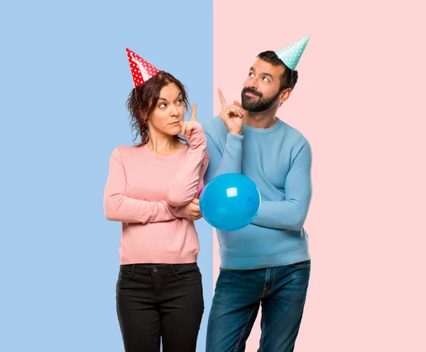 Casal Com Balões Chapéus Aniversário Apontando Com Dedo Uma Ótima — Fotografia de Stock